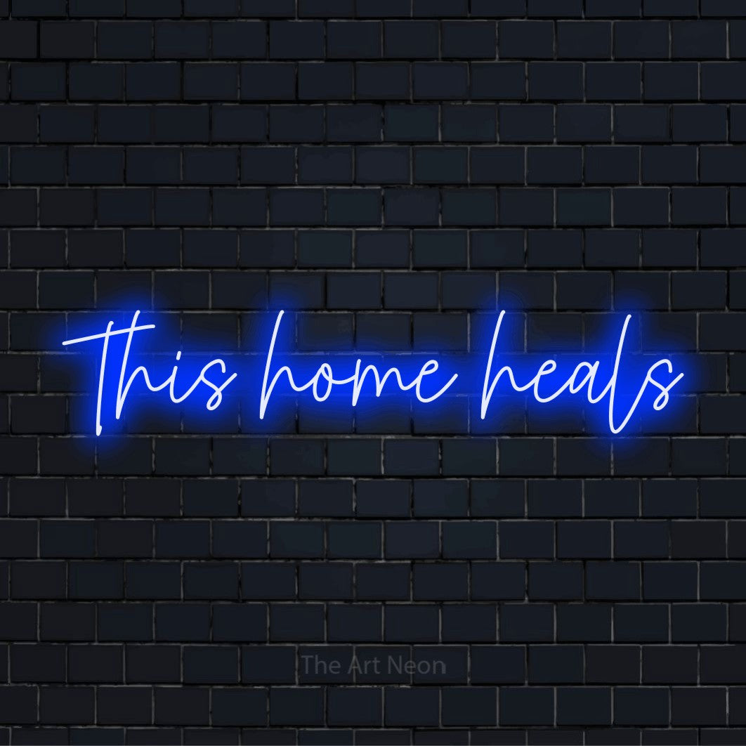 "This Home Heals" script-style LED neon sign on a black brick wall
