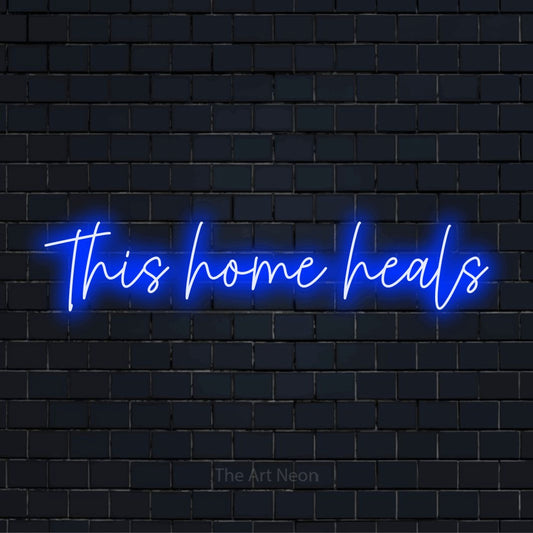 "This Home Heals" script-style LED neon sign on a black brick wall