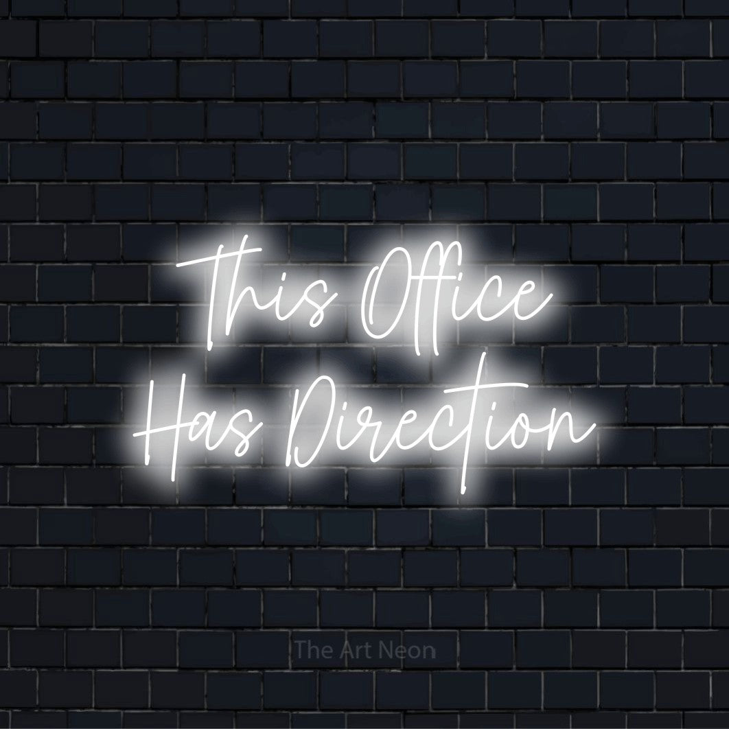 "This Office Has Direction" glowing LED neon sign on a black brick wall