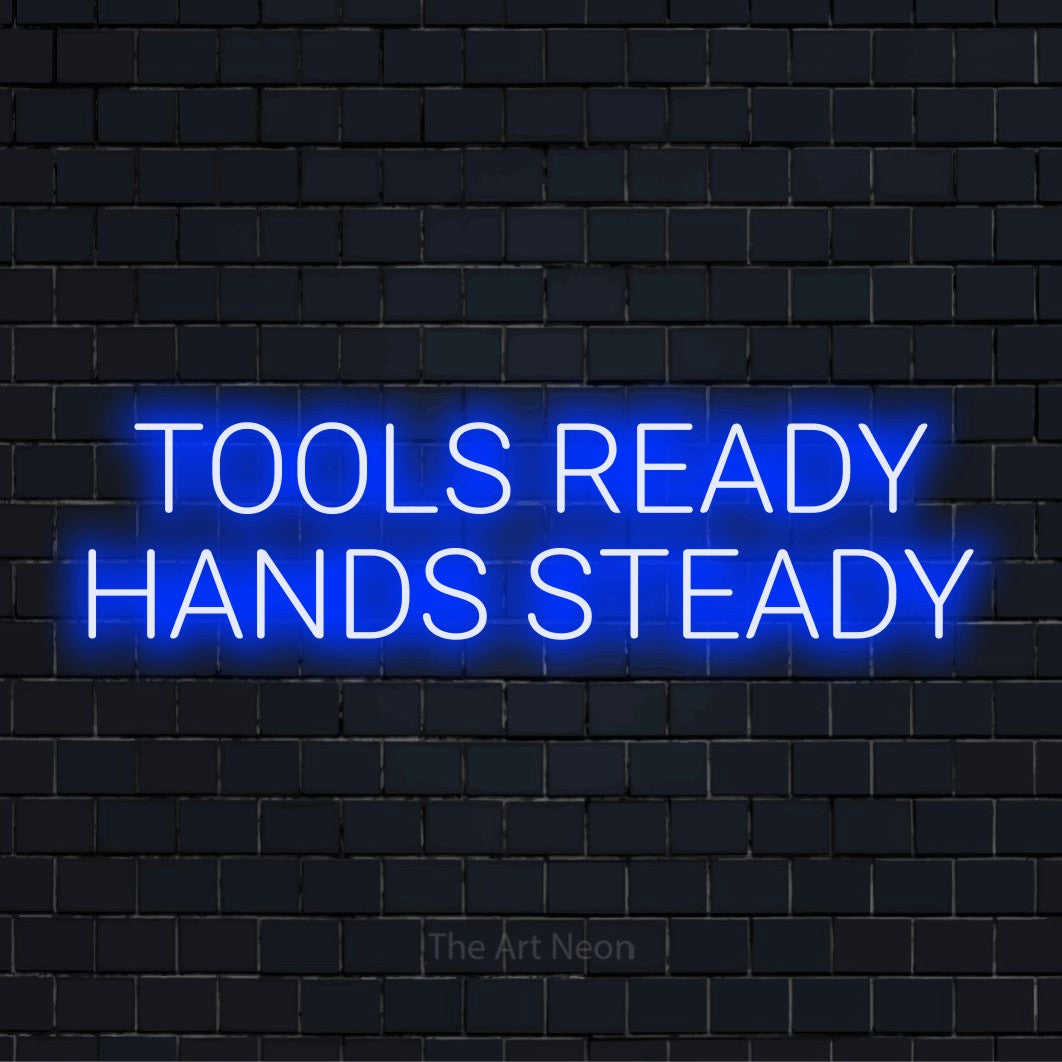 "Tools Ready Hands Steady" glowing LED neon sign on a black brick wall
