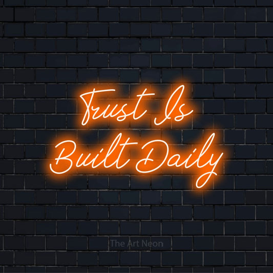 "Trust Is Built Daily" script-style LED neon sign on a black brick wall