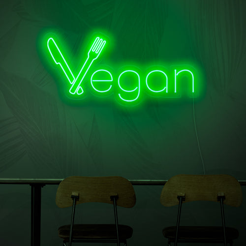 Neonkyltti, jossa lukee "vegaaninen", joka edustaa kasvipohjaisen keittiön konseptia sen eloisalla vihreällä valolla.