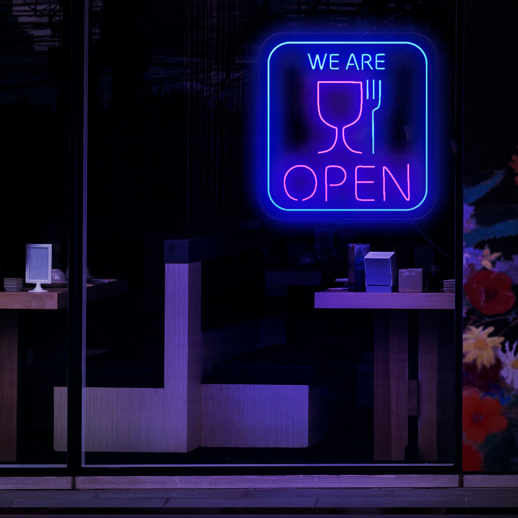 Kiehtova neonkyltti kupin ja haarukan symboleilla osoittaen, että ravintola tai ruokapaikka on avoinna liiketoiminnalle. 