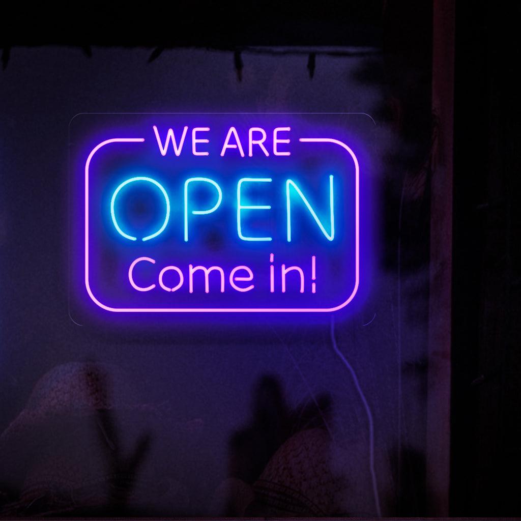 Kiehtova neonkyltti, jossa on lihavoituja, hehkuvia kirjaimia, joissa lukee "We Are Open". Tule sisään.' 