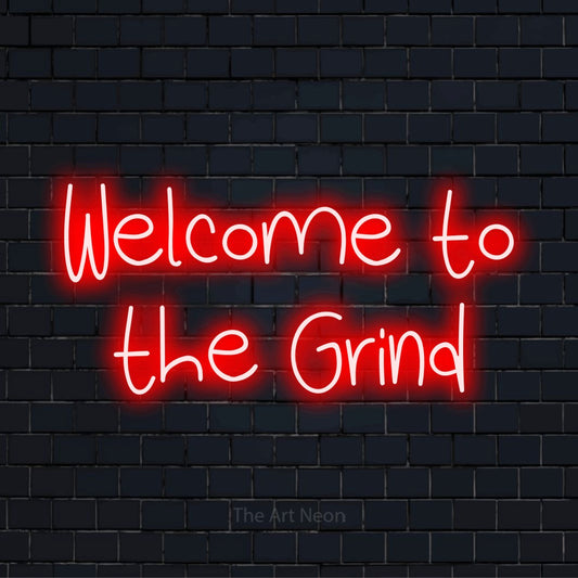 "Welcome To The Grind" script-style LED neon sign on a black brick wall
