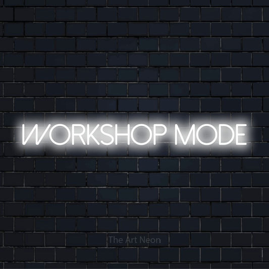"Workshop Mode" glowing LED neon sign on a black brick wall