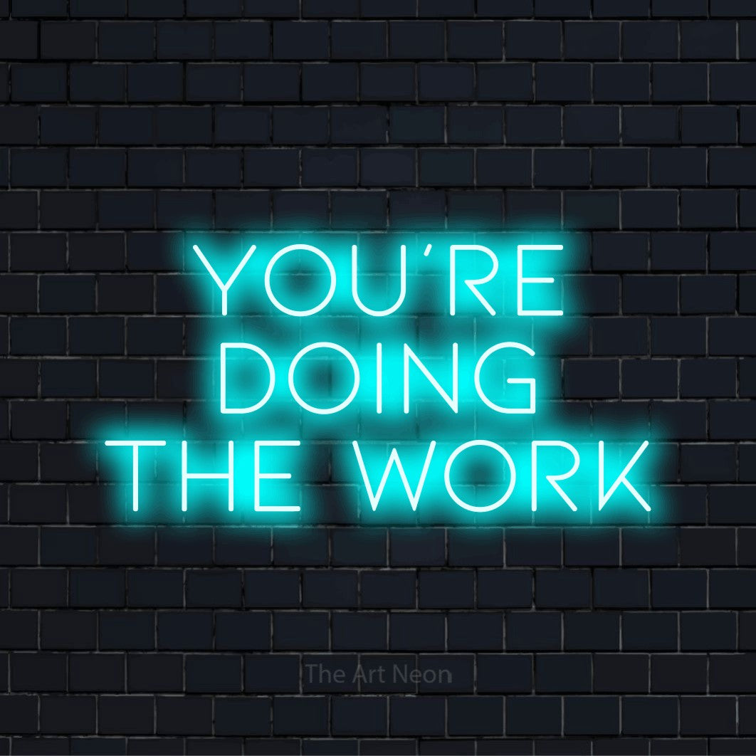 "You’re Doing The Work" text design with neon effect on a black brick wall