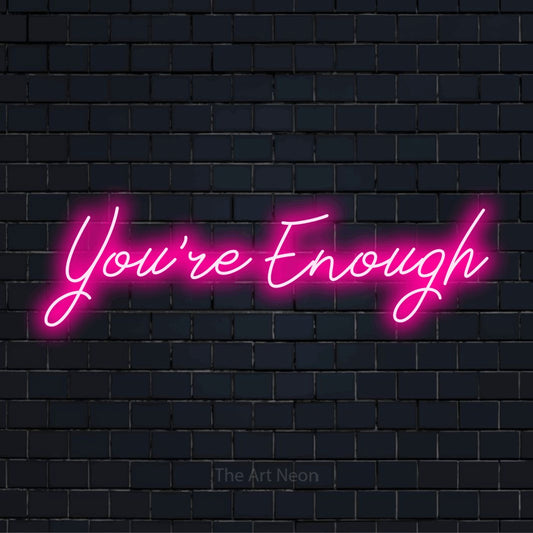 "You’re Enough" script-style LED neon sign on a black brick wall